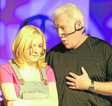 Szene aus dem Musical: die junge Sophie in Latzhose blickt betreten zur Seite, während ein älterer Darsteller mit Headset auf sie einredet