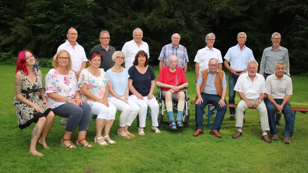 Die geehrten Jubilare sitzen und stehen im Freien vor dem Waldrand am Glaabsweiher, in der Mitte ein Jubilar im Rollstuhl