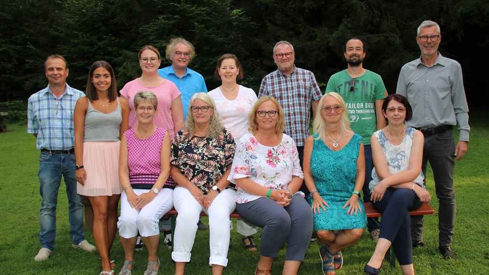 Das neu gewählte Vorstandsteam beim Gruppenfoto auf der Wiese vor Bäumen, vorne sitzen die Frauen auf einer Bierbank