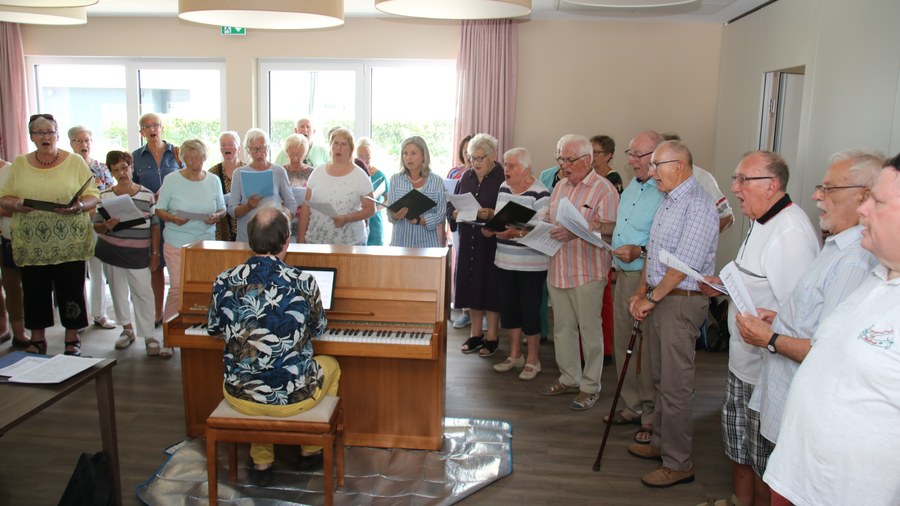 Der Chor ConTakt singt im Gemeinschaftsraum des Caritas-Hauses „Gabriel“, begleitet am Klavier