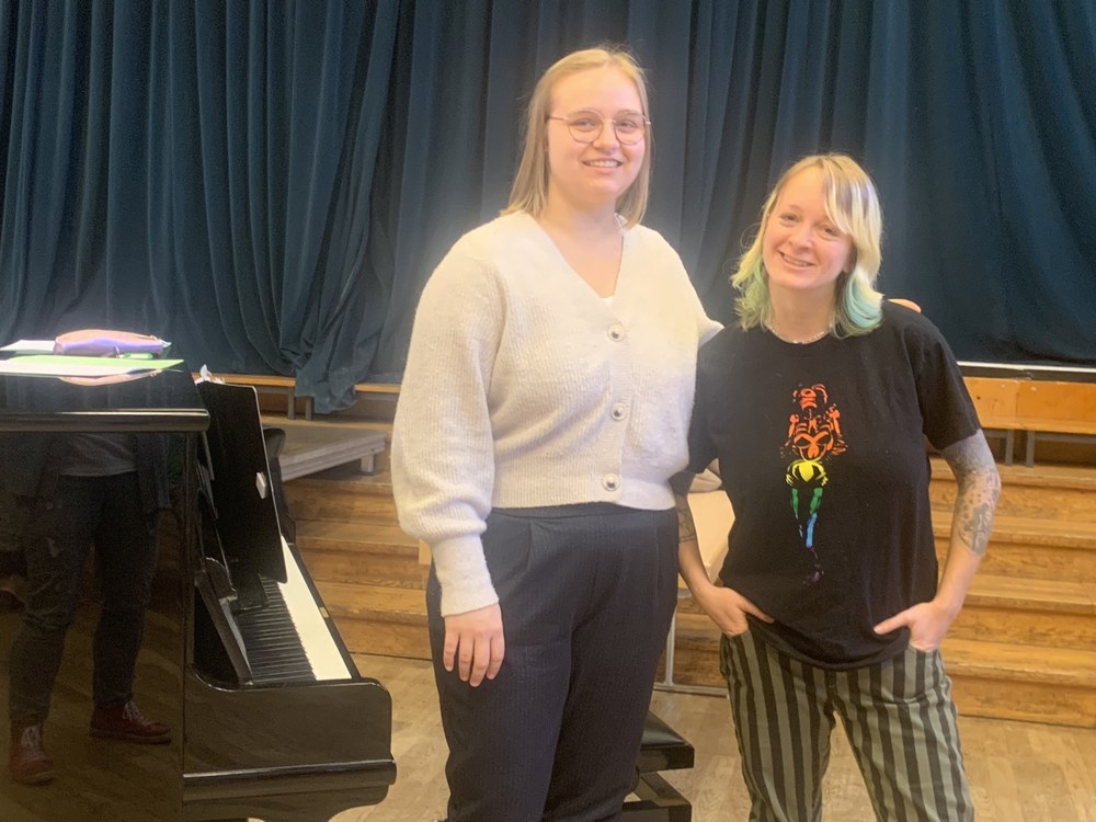 Die neue Kinderchorleiterin Annika Münch und ihre Vorgängerin Denise Oftring nebeneinander am Flügel im Bürgerhaussaal
