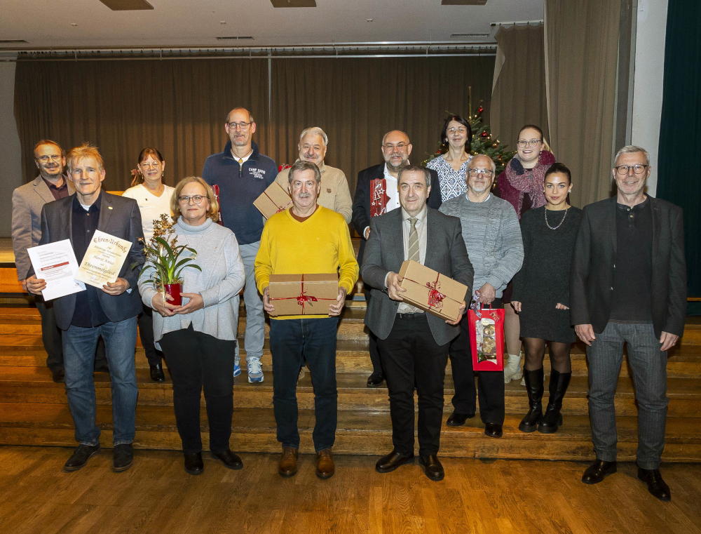 Die geehrten Mitglieder mit Urkunden und Geschenken vor der Bühne, im Hintergrund der Weihnachtsbaum